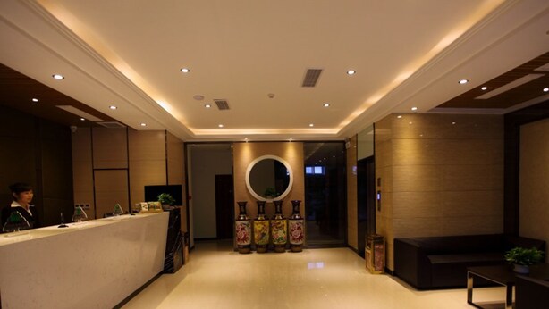 A hotel lobby with a reception desk, a round mirror, and a seating area.