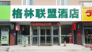 A hotel entrance with a green sign, a digital display indicating room rates, and a glass door.