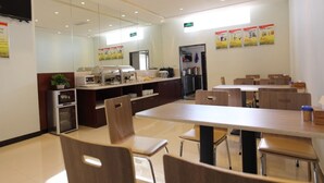 A modern dining area with a long table and chairs, a buffet station, and a refrigerator.
