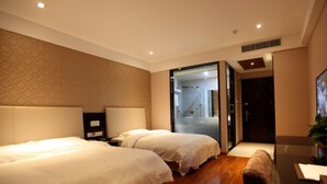 A hotel room with two beds, a large mirror, and a view of the bathroom through a glass door.