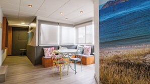 A modern interior with a seating area, a table, and a large window with a beach view. - Hotel del Mar (Vigo)