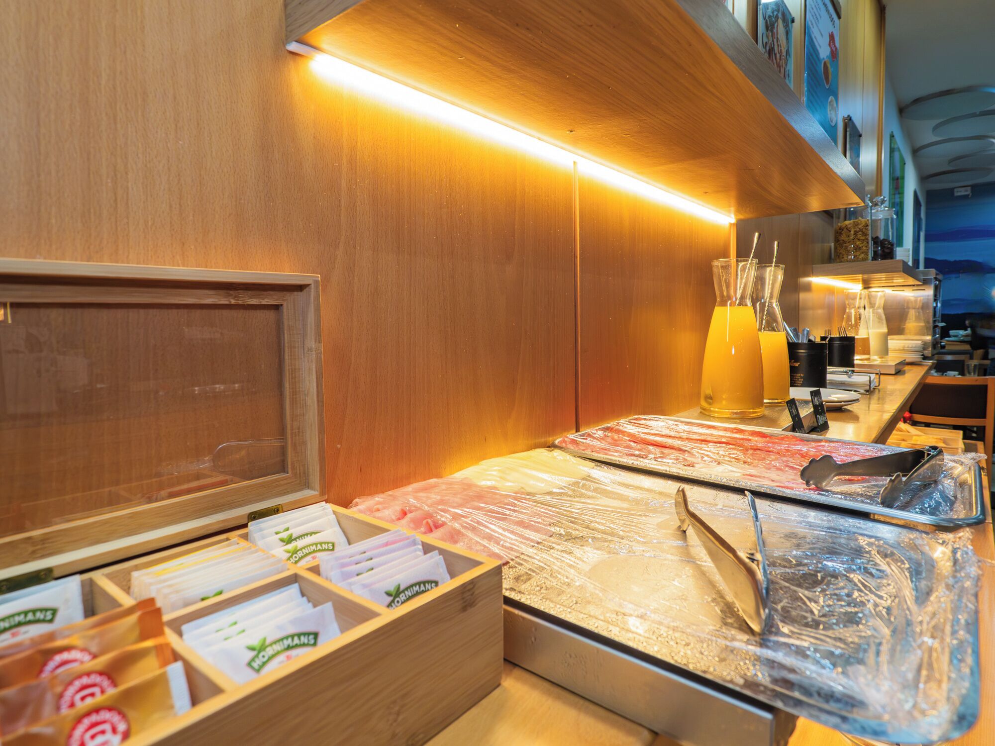 A kitchen area with a wooden counter, a drawer with packaged goods, and a glass container with a yellow liquid.