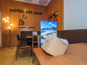 A hotel room with a wooden wall, a desk, a chair, a lamp, and a poster of a beach. - Hotel del Mar (Vigo)