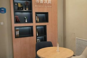 A room with a wooden wall, a round table, and black shelves with books and decorative items.