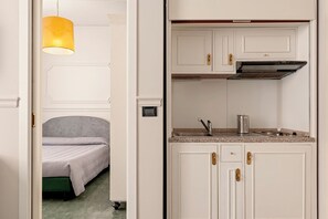Een kleine hotelkamer met een bed, een kitchenette en een hanglamp.