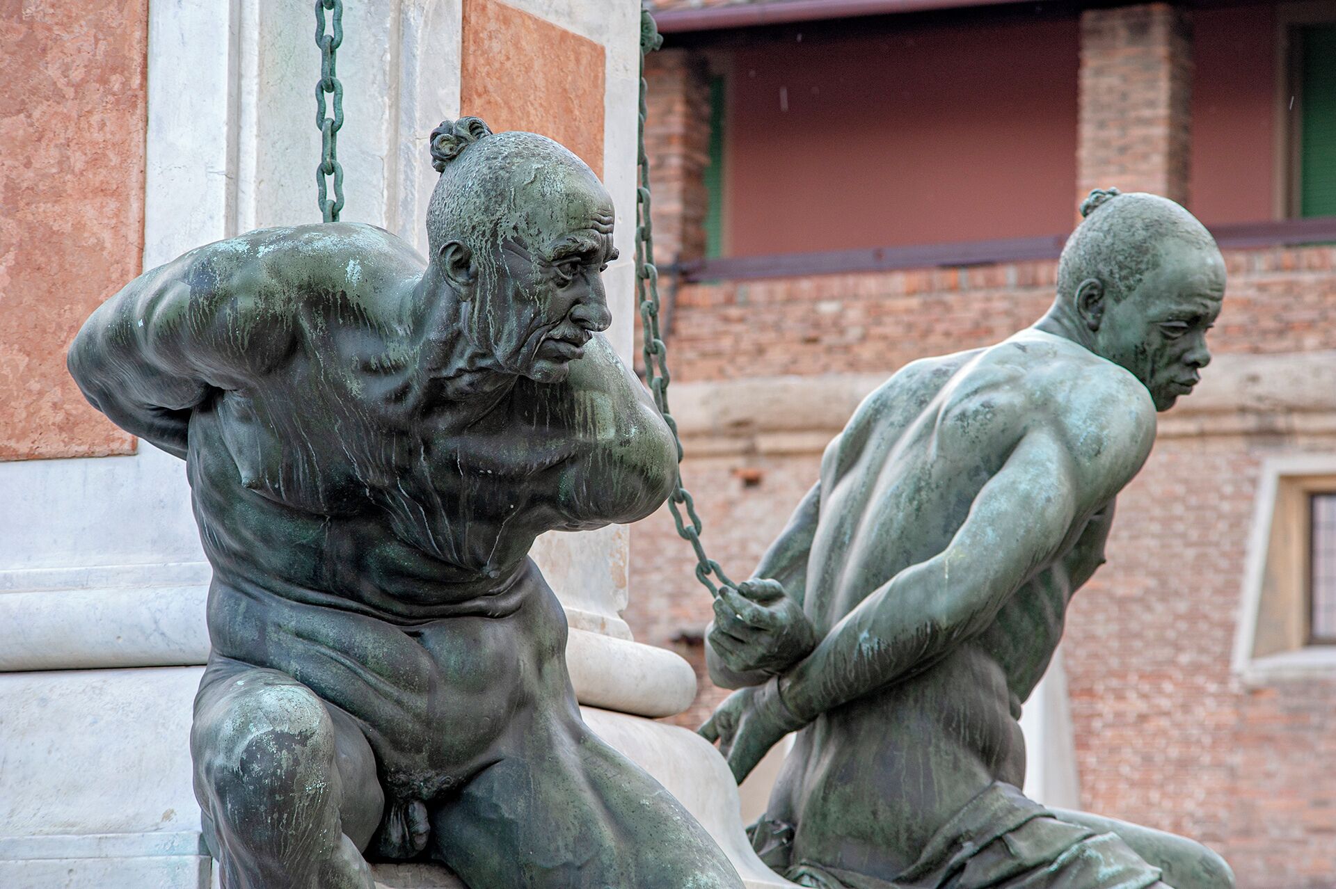 A statue of a seated man with a muscular build, holding a chain.