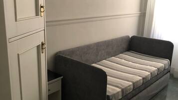 A modern room with a grey sofa, a white wardrobe, and a window with curtains.