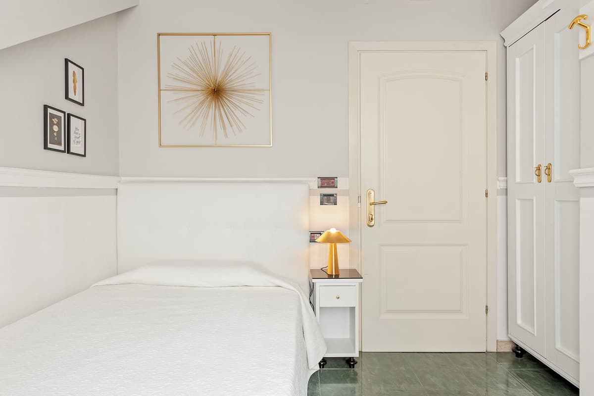 Une chambre à coucher avec un lit, une table de chevet avec une lampe, une porte et une armoire.