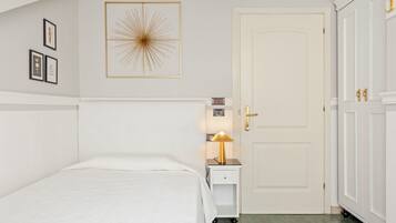 Een slaapkamer met een bed, nachtkastje met lamp, een deur en een kledingkast.