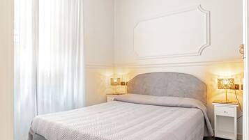 A neatly arranged bedroom with a bed, two bedside tables, and a wall-mounted light fixture.