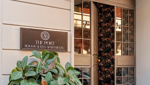 Een gevelingang met een bord waarop 'THE PORT ROOMS SUITES APARTMENTS' staat en het getal '5' erboven.