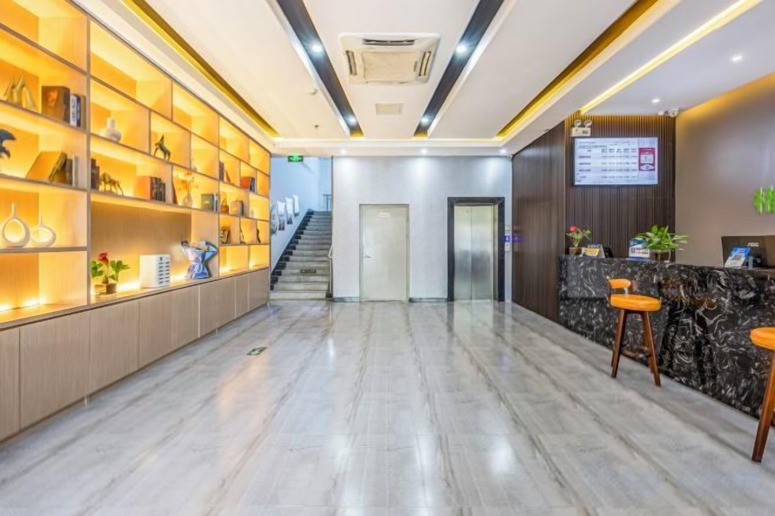 A hotel reception area with a marble floor, a reception desk, and a staircase leading to the upper floors.