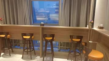 A bar area with wooden stools and a view of the street outside.