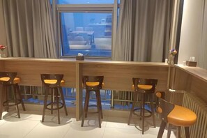 Een bar met houten krukken en uitzicht op de straat.