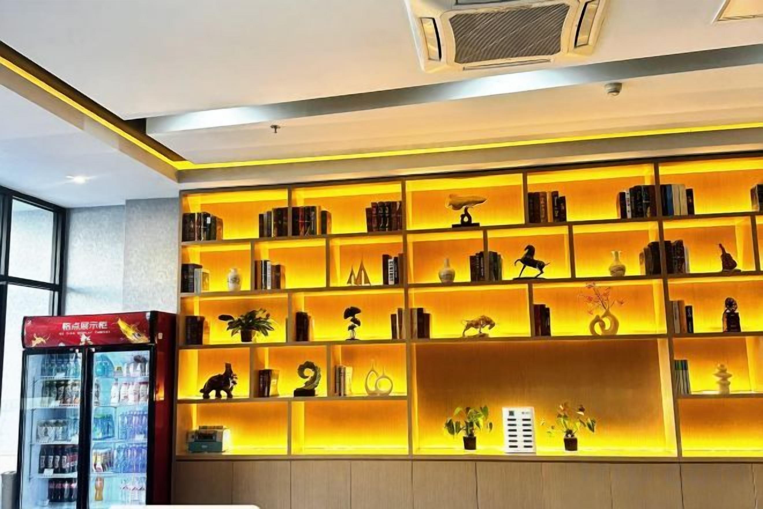 Un hall de hotel con una amplia y bien iluminada estantería llena de libros y objetos decorativos.
