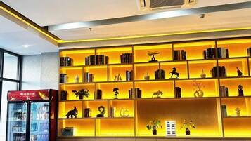 Un hall de hotel con una amplia y bien iluminada estantería llena de libros y objetos decorativos.