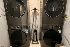 A laundry room with two front-loading washing machines and a central floor-standing dryer. - GreenTree Smart Choice Hotel (Beijing Liangxiang Nanguan Subway Station) (Beijing)