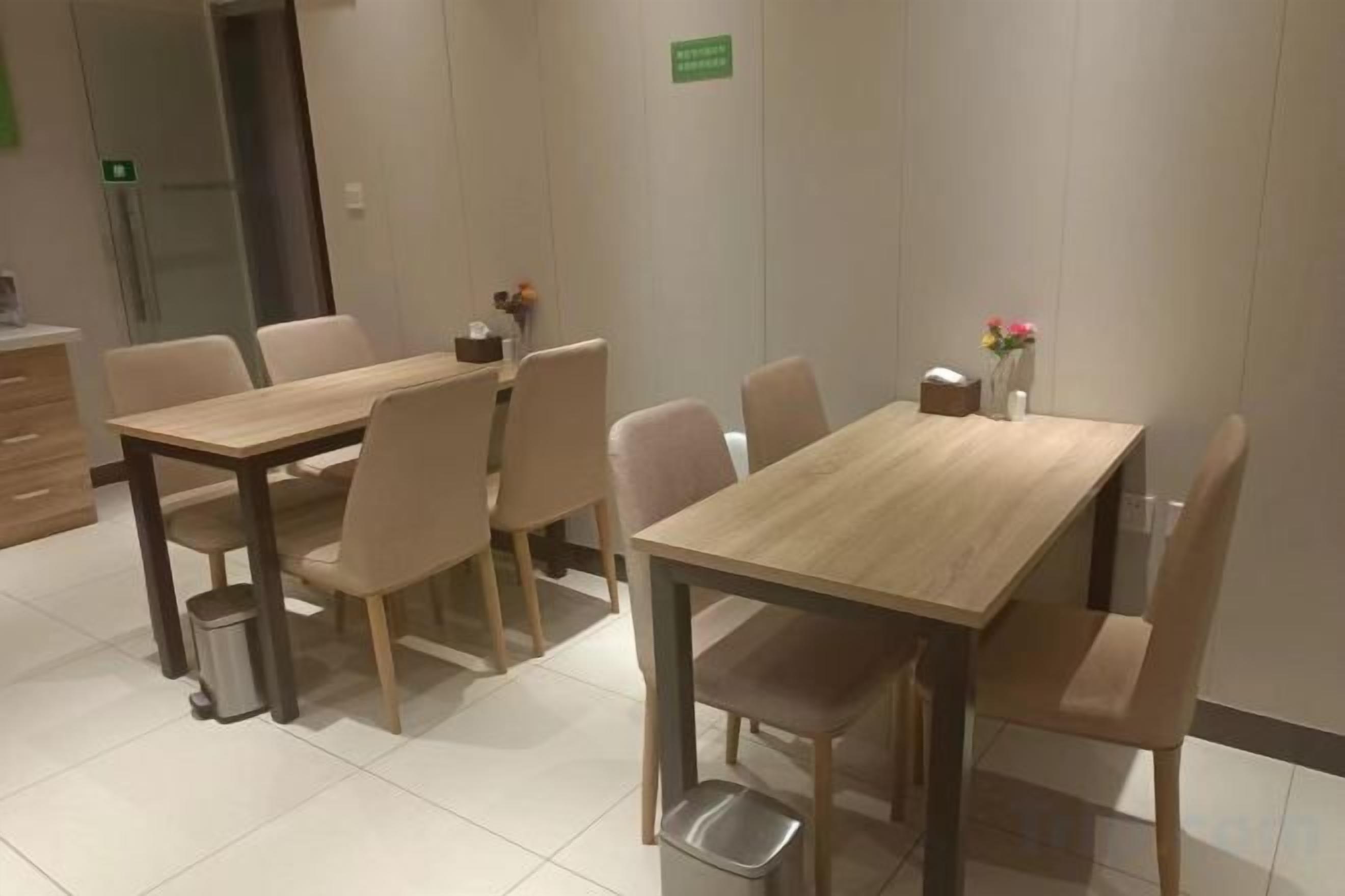 A hotel dining area with two wooden tables and multiple chairs.