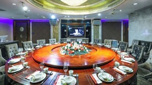 A conference room with a round table, chairs, a chandelier, and a television screen. - Jiehui Hotel (Shanghai)
