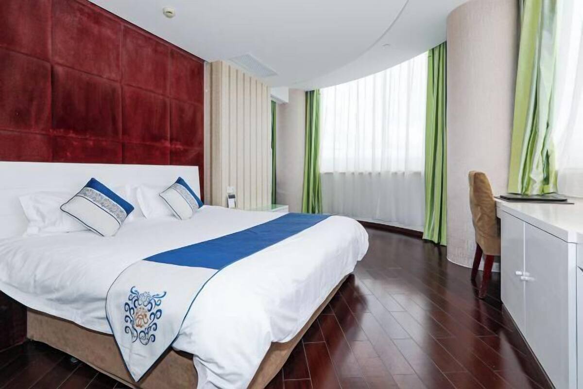 A hotel room with a large bed, a desk, and a chair.