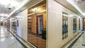 A hotel corridor with mirrored walls, chandeliers, and a marble floor. - Jiehui Hotel (Shanghai)