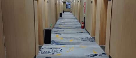 Un largo pasillo con paredes de madera y un suelo de alfombra estampada.