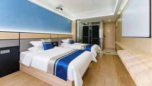Een moderne hotelkamer met twee bedden, een grote spiegel en een deur naar een badkamer.