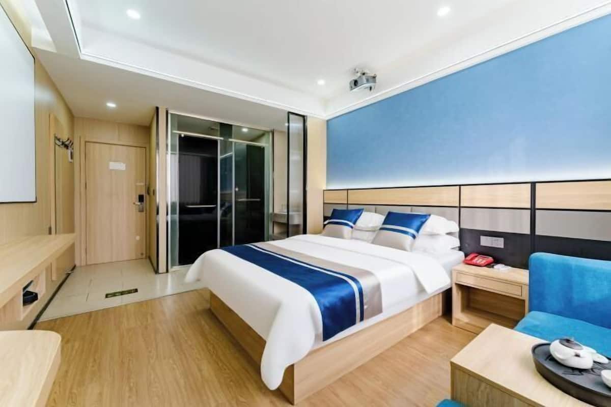 Une chambre d’hôtel avec un lit, une table de chevet et un mur bleu.