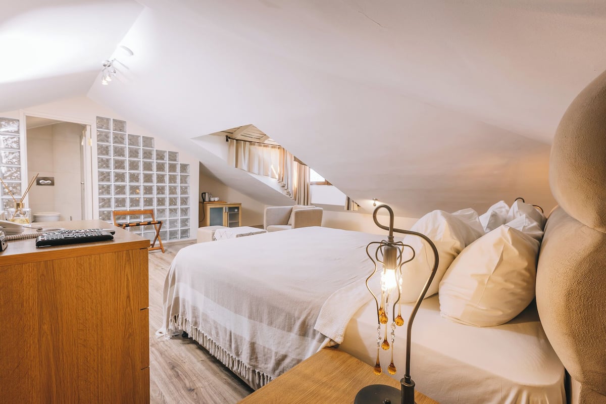 Un dormitorio con cama, escritorio, silla y ventana con cortinas.