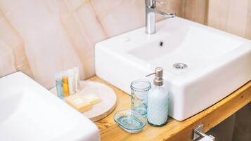 A bathroom with a white sink, a wooden countertop, and toiletries including soap, shampoo, and a bottle of lotion.
