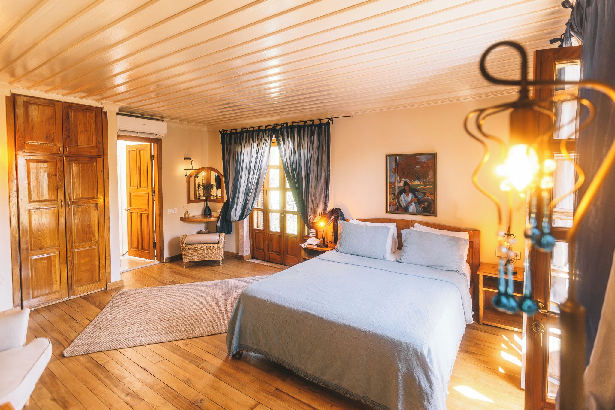 A spacious bedroom with a large bed, wooden flooring, and a wooden ceiling.