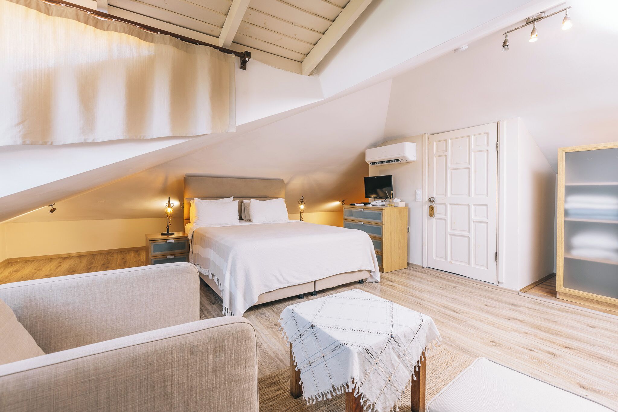 A bedroom with a bed, bedside tables, a nightstand, a small table with a tablecloth, a chair, and a wardrobe.
