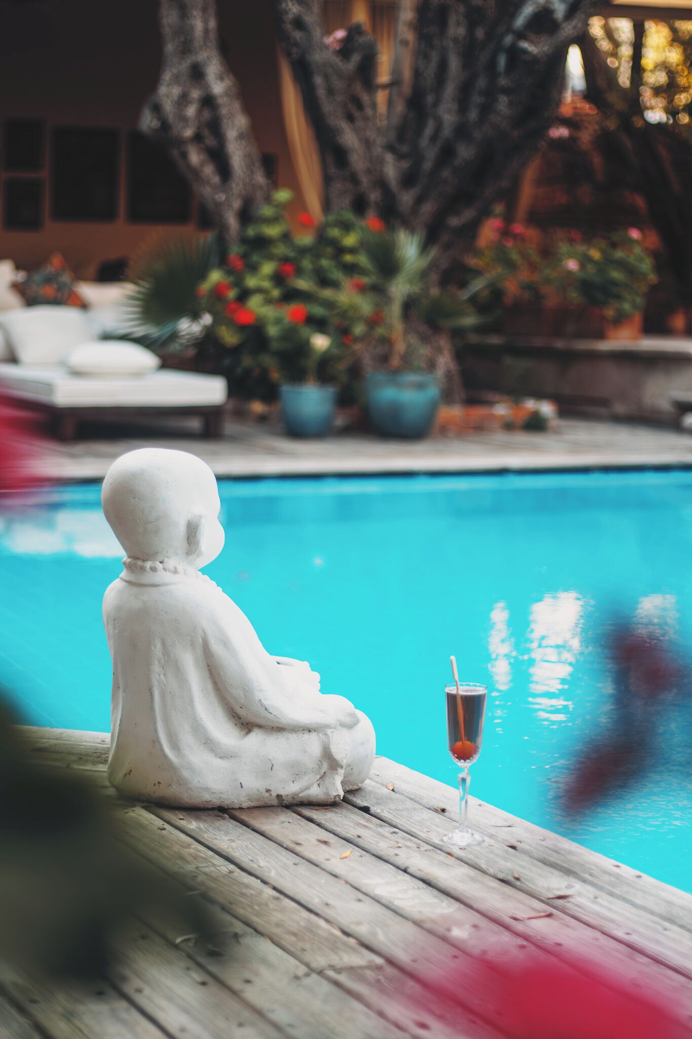 Una estatua junto a una piscina con una copa de champán.