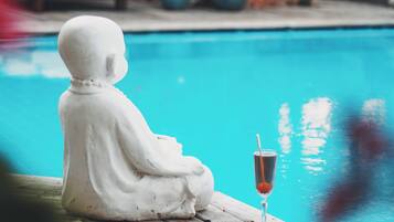 Una estatua junto a una piscina con una copa de champán.