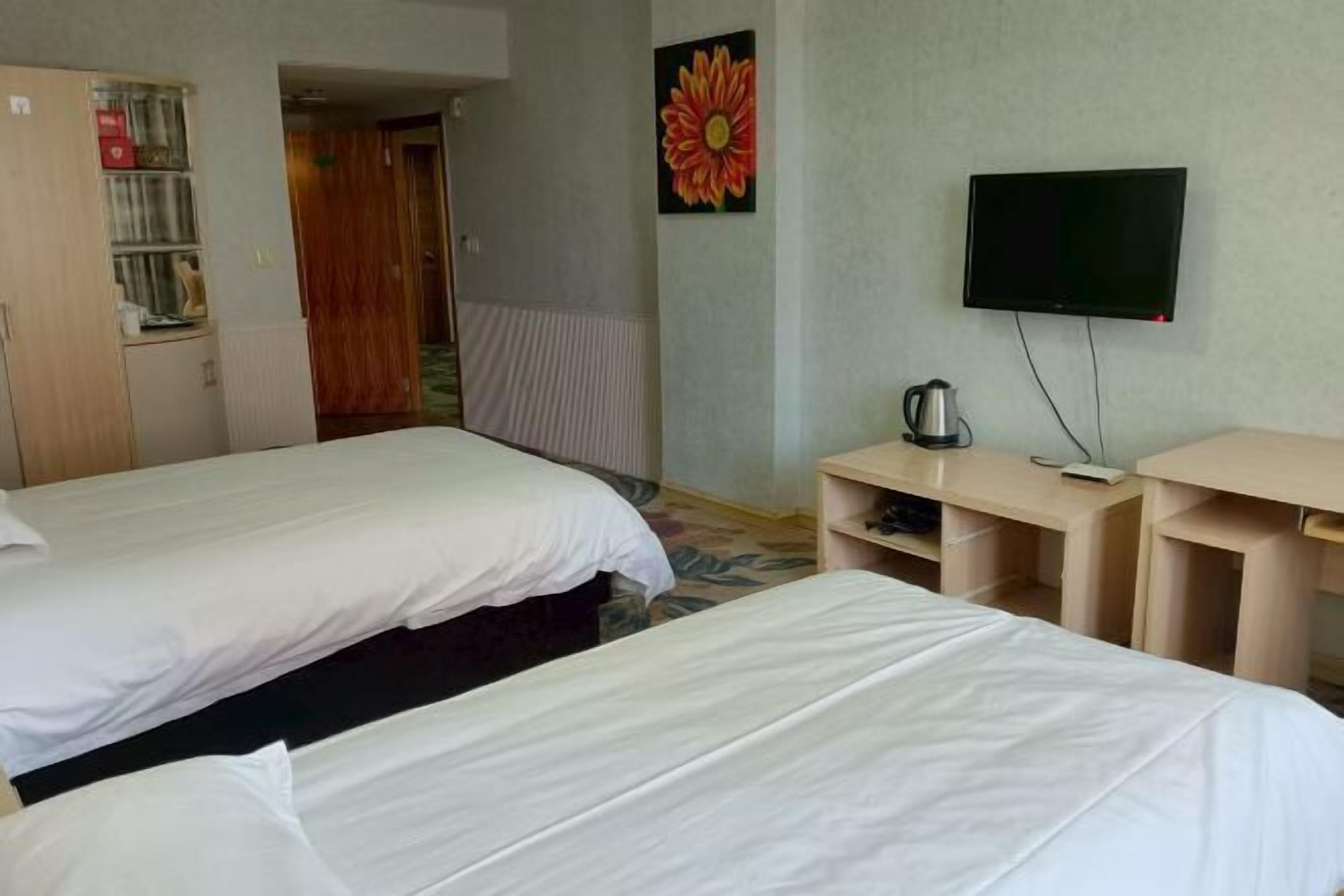A hotel room with two beds, a television, a coffee maker, and a painting on the wall.