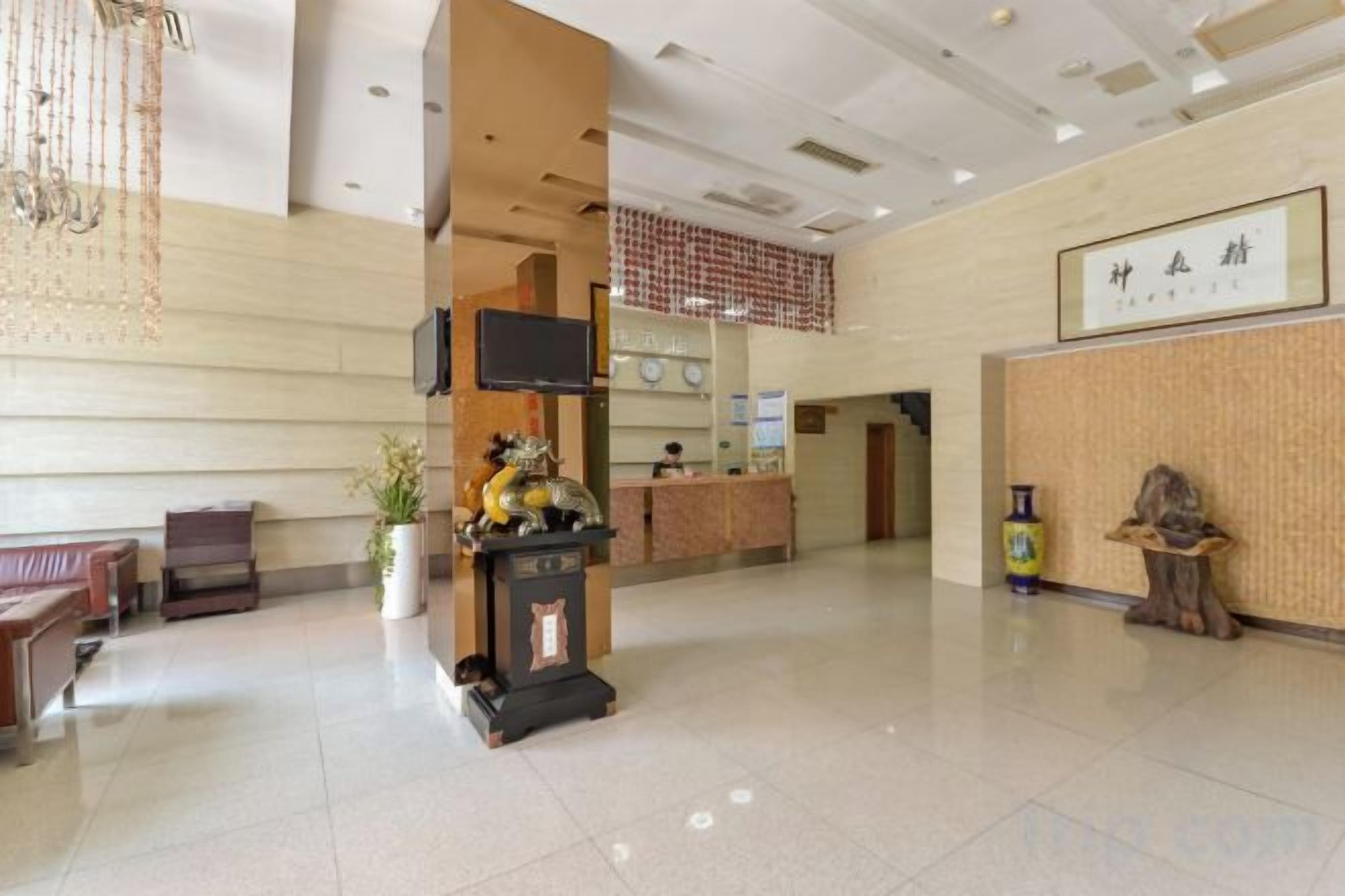A hotel lobby with a reception desk, seating area, and a television mounted on the wall.