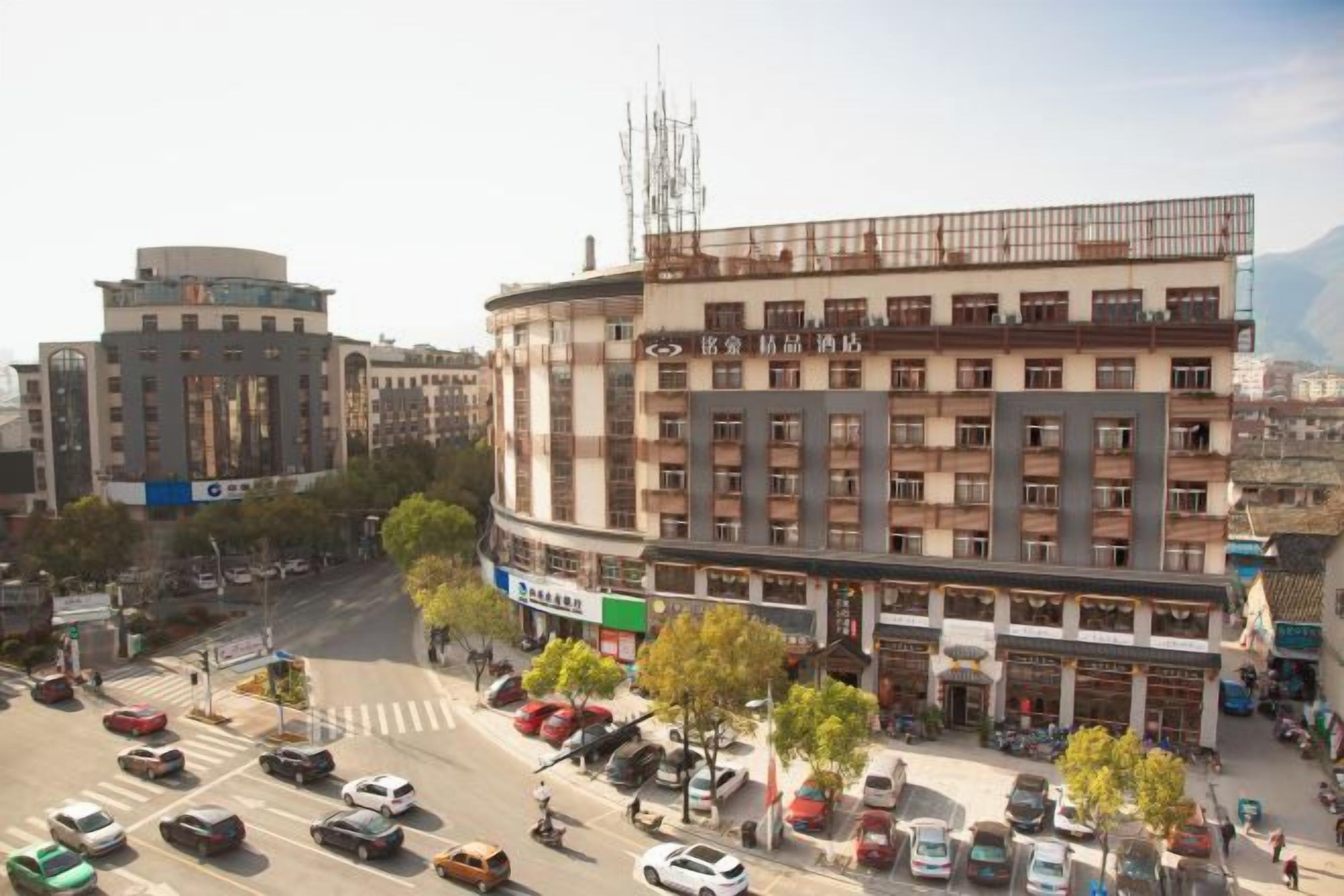 A multi-story building with a commercial ground floor, surrounded by a busy street with cars and pedestrians.