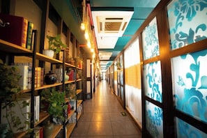 A corridor with shelves on the left and patterned glass doors on the right. - Minghao Hotel (Xianju)