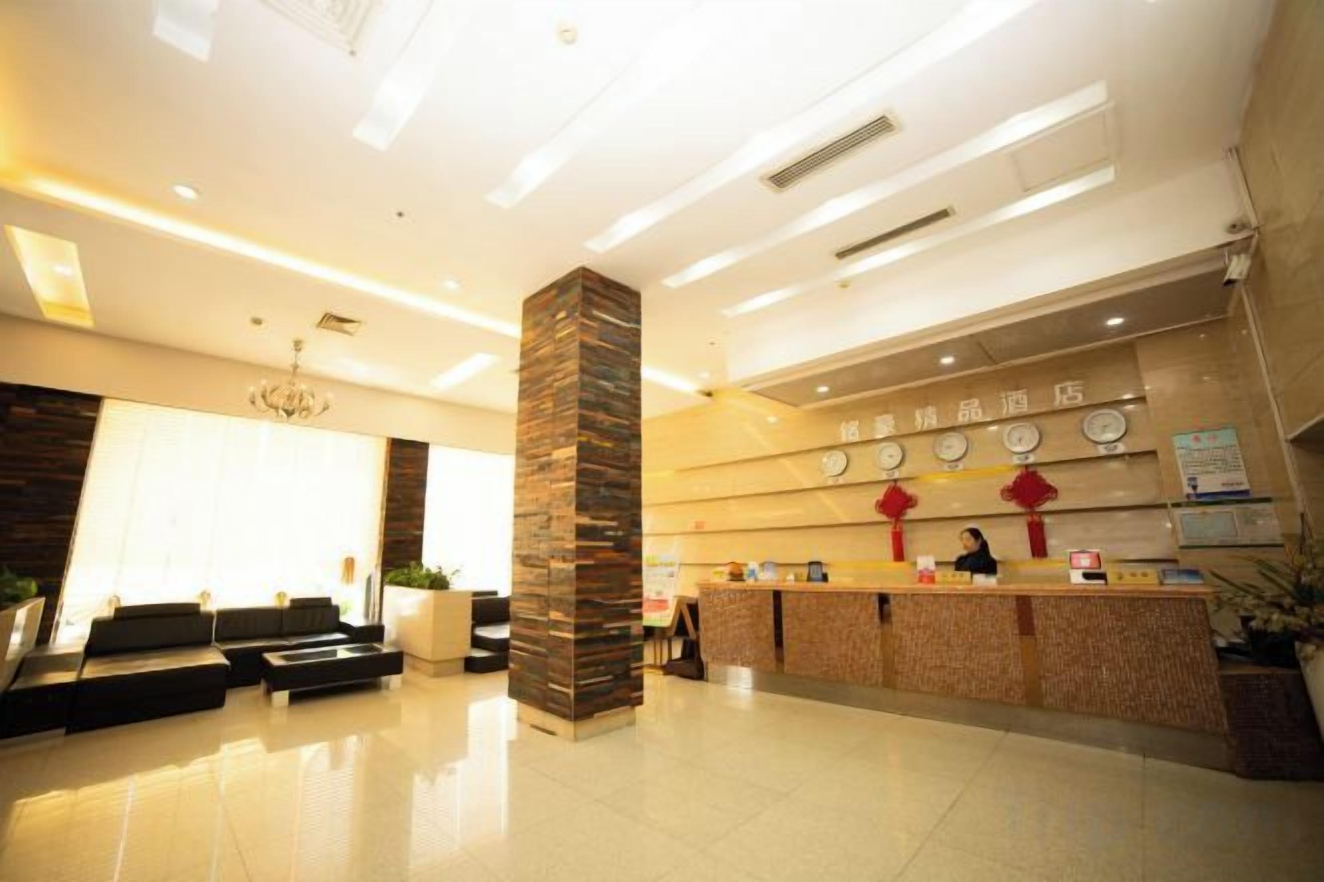 A hotel reception area with a reception desk, seating area, and a large pillar.