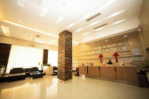 A hotel reception area with a reception desk, seating area, and a large pillar. - Minghao Hotel (Xianju)