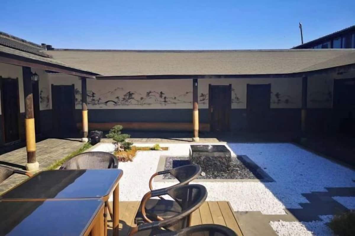A courtyard with a wooden deck, outdoor seating, and a mural on the wall.