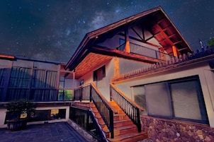 Una casa moderna con escalera de madera, balcón y pared de piedra.