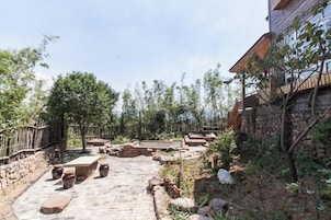 Un patio al aire libre con estructuras de piedra, un camino de ladrillo y una valla de madera.