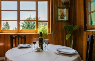 Mesa posta com copos de vinho, pratos e uma garrafa de vinho.