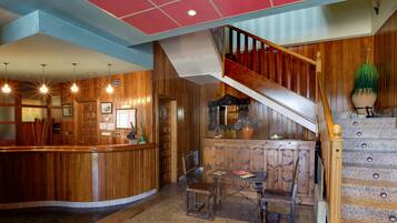 A reception area with a wooden counter, a staircase, and a seating area with a table and chairs.