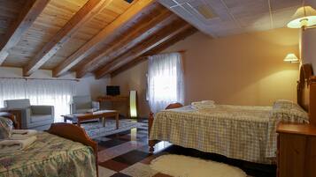 Una habitación acogedora con techo de madera, una cama con colcha a cuadros, dos sillones, una mesita y un televisor.