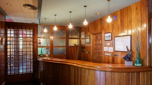 A reception desk with wooden paneling, a glass partition, and a reception area with a sign indicating WiFi availability. - Hostal Casa Ramón III (Quintanar de la Sierra)