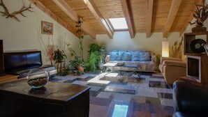 A cozy living room with a wooden ceiling, a sofa, a coffee table, and a fireplace. - Hostal Casa Ramón III (Quintanar de la Sierra)