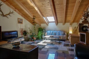 Uma sala de estar aconchegante com teto de madeira, um sofá, uma mesa de centro e uma lareira.