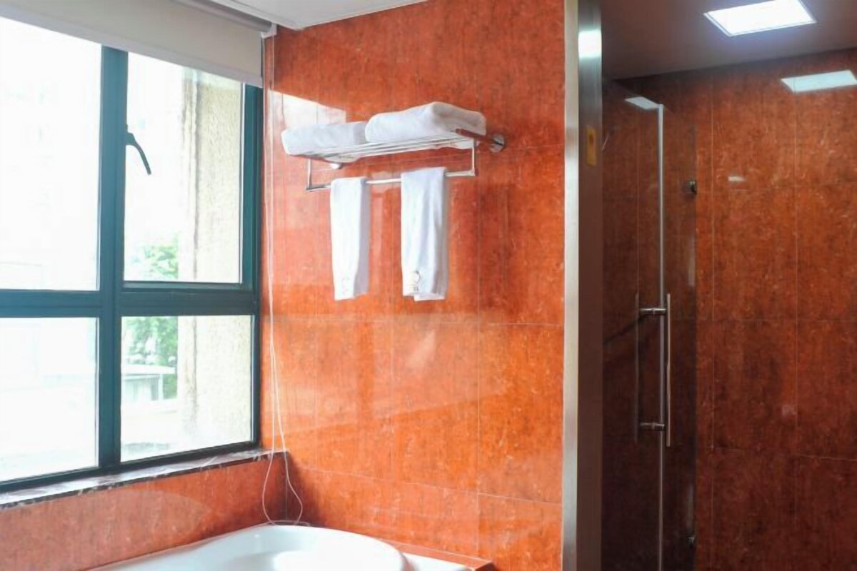 Ein Badezimmer mit einer Badewanne, einer Dusche und einem Fenster.
